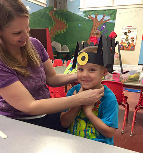 Teacher Debbie Helping Student Adjust His Spooky Spider Hat